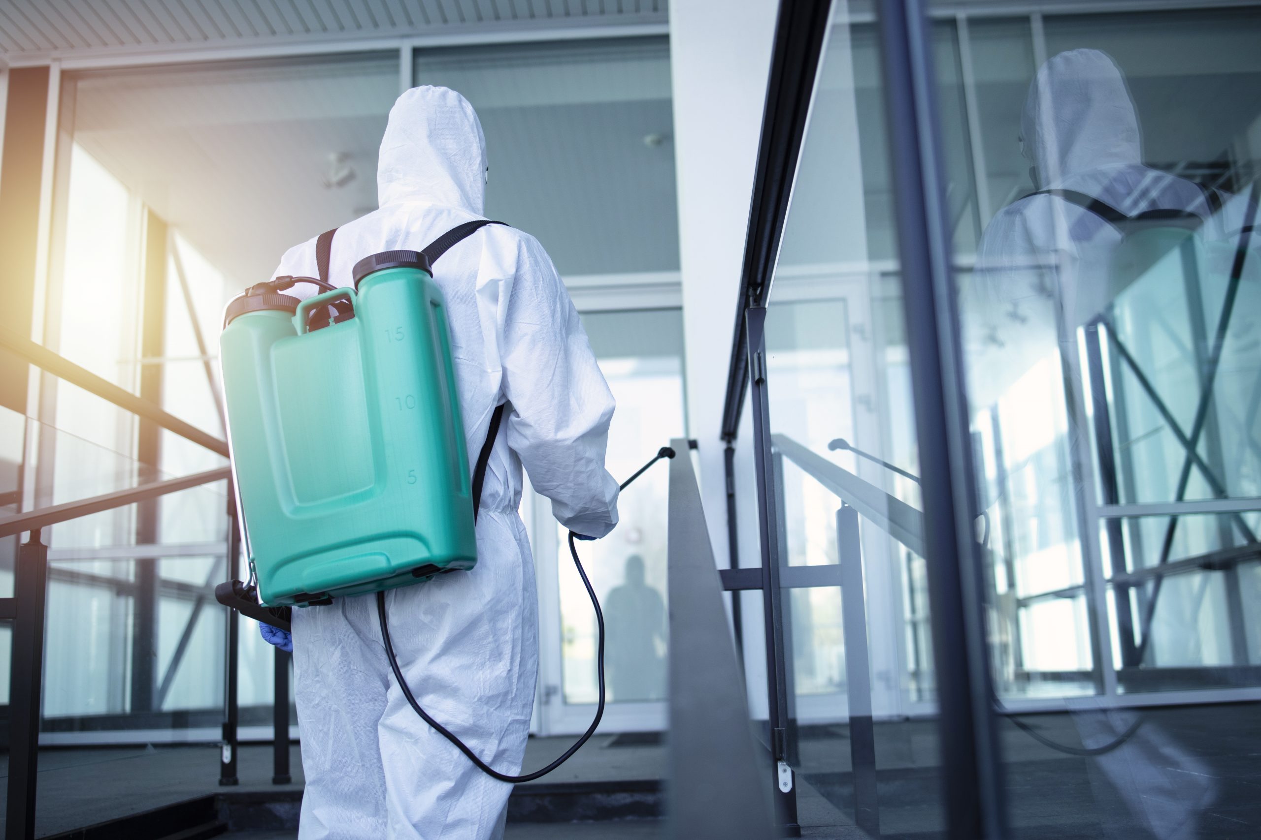 Man with tank reservoir on his back spraying disinfectant to stop corona virus.