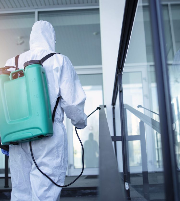 Man with tank reservoir on his back spraying disinfectant to stop corona virus.